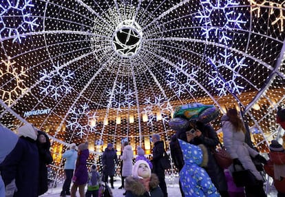 Varias personas caminan dentro de una gran bola decorativa de Navidad en la plaza Octyabrskaya durante las fiestas de Navidad y de Año Nuevo en Minsk (Bielorrusia).