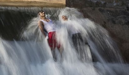 Dos hombres se bañan para combatir el calor en las afueras de Islamabad, Pakistán.