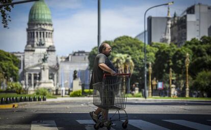 Un hombre con un carrito de supermercado cruza la Avenida de Mayo el 27 de marzo de 2020 en Buenos Aires, Argentina.