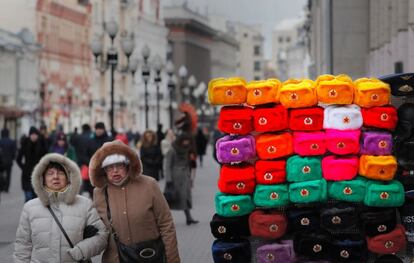 Dos mujeres pasan frente a una tienda con gorros Ushanka a la venta en diferentes colores, en el centro de Moscú (Rusia).