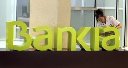 Una operaria limpia el logo de Bankia. 