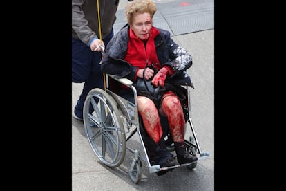 Una mujer con las piernas ensangrentadas es evacuada en una silla de ruedas.