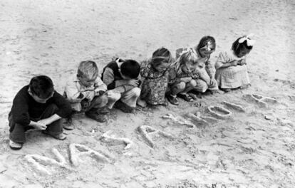 Egipto, 1946. Niños yugoslavos miran las palabras 'nasa skola' (nuestra escuela, en servocroata) escritas en la arena, en el campo de refugiados del UNRRA en Tolumbat. Lápices, bolígrafos y papel escasean en el campamento y se reservan para los escolares de mayor edad.