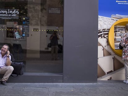 Una persona habla por teléfono mientras espera para poder utilizar un cajero automático en Sevilla.