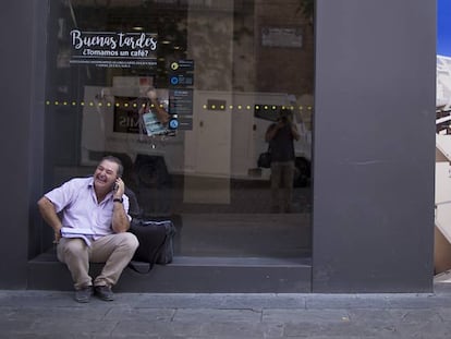 Una persona habla por teléfono mientras espera para poder utilizar un cajero automático en Sevilla.