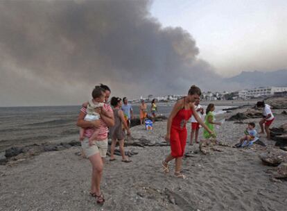 Vecinos y veraneantes abandonan la playa de Mojácar cercada por el humo.