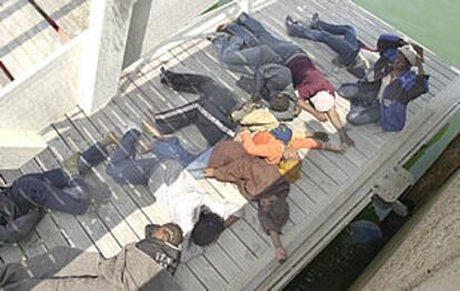 Inmigrantes rescatados ayer frente al cabo de Trafalgar descansan en el muelle de Barbate.