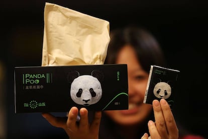Una mujer sujeta dos paquetes de pañuelos Panda Poo, fabricados con excrementos de osos panda.