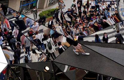 Un grupo de gente se refleja en unos espejos de una zona comercial de Tokio (Japón).