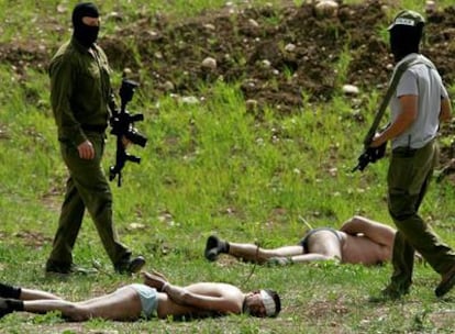 Miembros de las fuerzas especiales israelíes, metralleta en mano, vigilan a dos palestinos semidesnudos y esposados con bridas de plástico cerca de Latrun.