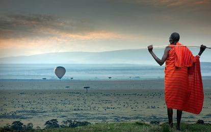 Un hombre masai mira un globo aerostático sobre la sabana.