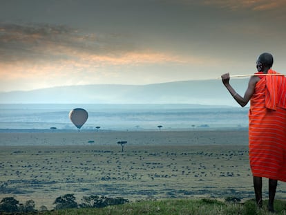Un hombre masai mira un globo aerostático sobre la sabana.