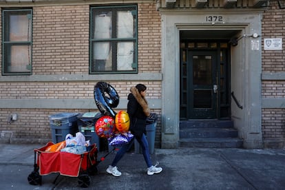 Una mujer pasa por delante de la entrada de un apartamento donde agentes de ICE llevaron a cabo una redada en Nueva York.