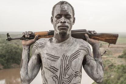 Un hombre de la tribu Kara de Korcho, junto al río Omo, posa con los ojos cerrados ("Ape dumma" en su lengua), el cuerpo pintado con arcilla blanca y su más preciada posesión: un rifle Kalashnikov AK-47. El aumento de las armas y el alcohol entre las tribus se relaciona no solo con el incremento de los enfrentamientos intertribales, sino sobre todo con la eliminación de los sistemas tradicionales de supresión de conflictos.