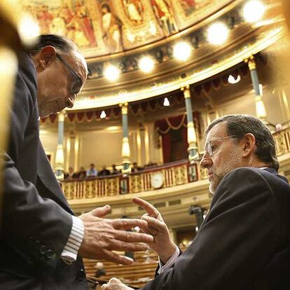 Mariano Rajoy, a la derecha, conversa en su escaño con Cristóbal Montoro en el Congreso.