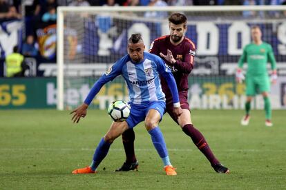 El delantero marroquí del Malaga, Youssef En-Nesyri (i), protege el balón ante el acoso del defensa del FC Barcelona, Gerard Piqué.
