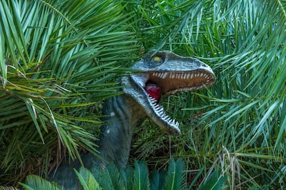 Figura de un velociraptor en el jardín de la mansión.