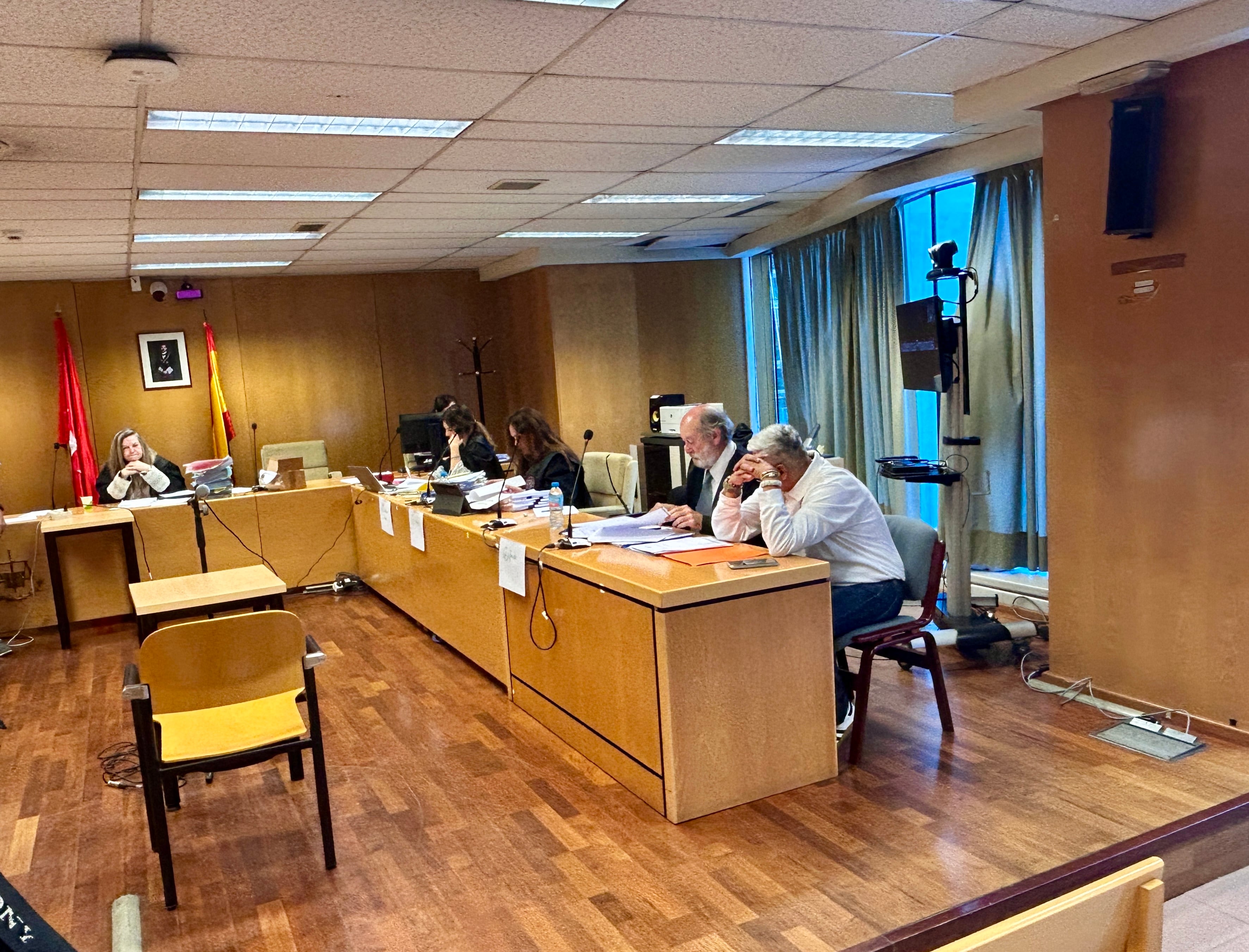 El acusado, en primer plano, y la acusada, detrás de la cortina, en la segunda jornada de la sesión del juicio por el crimen de un hombre al que luego quemaron en Vallecas.