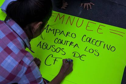 Alejandra Soto, miembro de MNUEE, escribe una pancarta para protestar frente a un edificio del Poder Judicial en la Ciudad de México.
