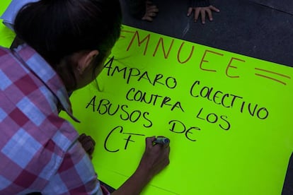 Alejandra Soto, miembro de MNUEE, escribe una pancarta para protestar frente a un edificio del Poder Judicial en la Ciudad de México.