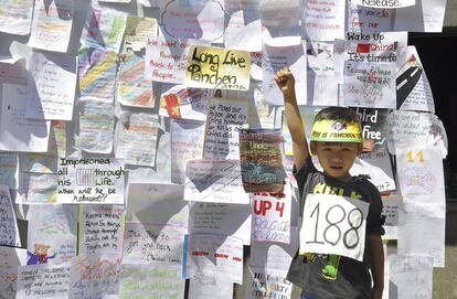 Un niño posa delante de una pared cubierta con mensajes de activistas tibetanos con motivo de la conmemoración del 21 aniversario del secuestro de un niño tibetano de siete años considerado como la reencarnación del Panchen Lama, en Dharamshala, India.