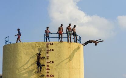 Jóvenes indios saltan al río Buriganga para refrescarse durante un día caluroso en Daca (Bangladés)
