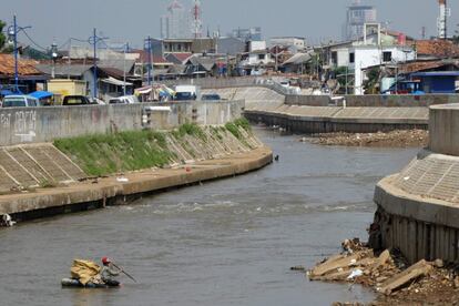 Un hombre permanece sentado en una balsa mientras intenta recolectar materiales reciclables en un río del centro de Yakarta (Indonesia).