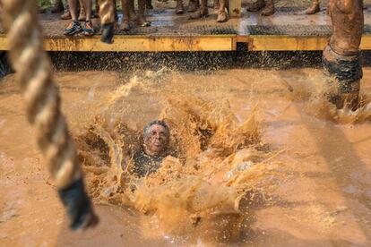 Uno de los participantes cae al lodo durante la carrera de obstáculos.