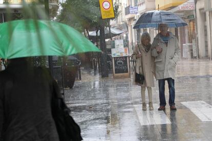 Varias personas se protegen de la lluvia en Gandía este jueves.