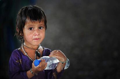 Una joven afgana sostiene una botella de agua en el centro de registro para refugiados instalado en las afueras de Peshawar, Pakistán, donde se estima que hay 1,9 millones de refugiados.