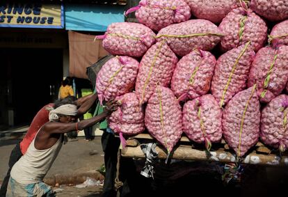 Dos trabajadores empujan un carro cargado de cebollas cerca de un mercado mayorista de verduras en Calcuta (India).  