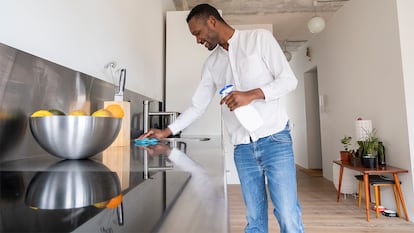 Un hombre limpiando su cocina de acero inoxidable con abrillantador