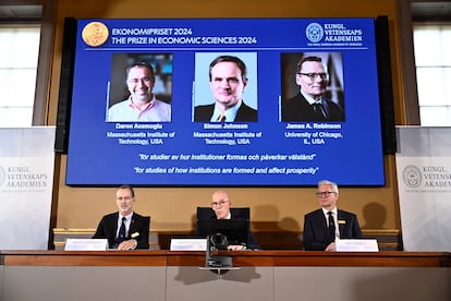 La Academia sueca anuncia los nombres de los ganadores del Nobel de Economía Daron Acemoglu, Simon Johnson y James A Robinson, que aparecen en la pantalla.