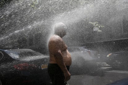 Un hombre se moja frente a una boca de incendios en una calle de Nueva York (EE UU). Estados Unidos registró 1.592 muertes por covid-19 en 24 horas, el peor balance diario desde hace dos meses y medio.