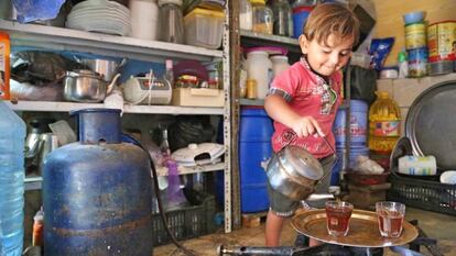 Un niño sirve el té en la cocina de su casa.