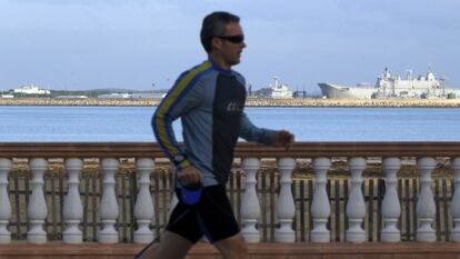 Un hombre corre por el paseo marítimo, con la base militar al fondo. 