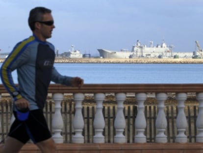 Un hombre corre por el paseo marítimo, con la base militar al fondo. 