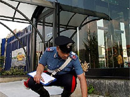 Un <i>carabinieri</i> recoge pruebas del artefacto explosivo colocado junto al concesionario de Fiat