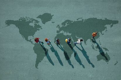 People walking in line across world map, painted on asphalt, front person walking left