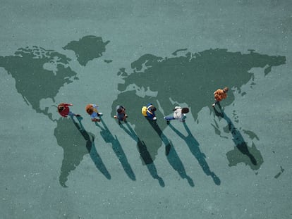 People walking in line across world map, painted on asphalt, front person walking left
