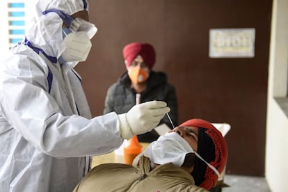 Un sanitario hace una PCR a un agente de policía, en el Centro de Salud Comunitario a las afueras de Amritsar, India.