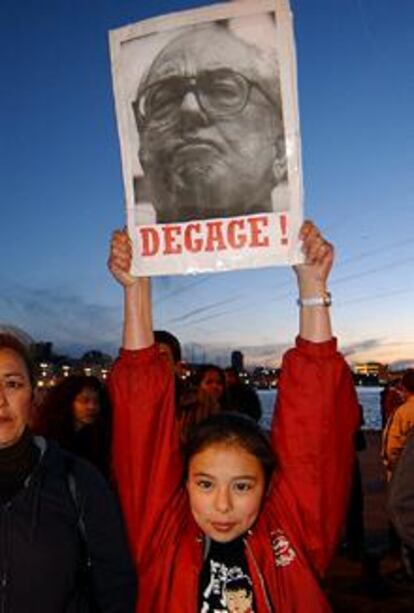 Una mujer levanta un cartel con una foto de Le Pen y la palabra <i>fuera</i> en una manifestación en Marsella.