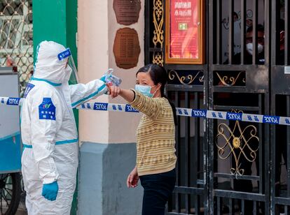 Un guardia de seguridad vestido con equipo de protección ordena a una mujer volver a su casa para guardar cuarentena, en Shanghai, este martes.