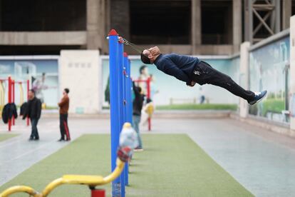 Sun Rongchun, de 57 años, hace ejercicios con un dispositivo de tracción cervical conectado a una barra de en un complejo deportivo en Shenyang (China).