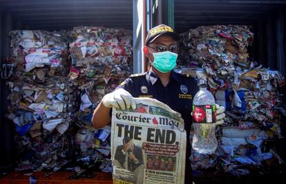 Un policía indonesio de aduanas muestra un periódico y una botella de plástico sacadas de un contenedor con una mezcla de basura, plásticos y residuos peligrosos enviados por Asutralia al puerto de Surabaya, en Indonesia. Las autoridades indonesias devolverán a Australia 210 toneladas de basura contaminada.