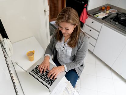 Una mujer realiza un trámite en línea desde su hogar, en una fotografía ilustrativa.