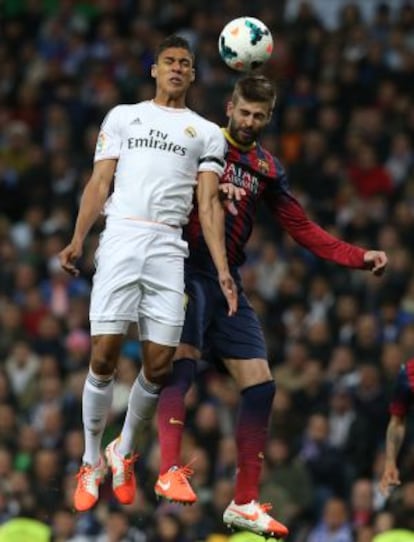 Varane y Piqué pugnan por un balón en el clásico.