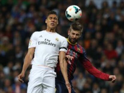 Varane y Piqué pugnan por un balón en el clásico.