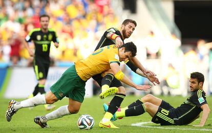 Mile Jedinak de Australia pelea por el bal&oacute;n con Sergio Ramos ante la mirada de Cesc F&aacute;bregas en el suelo. 