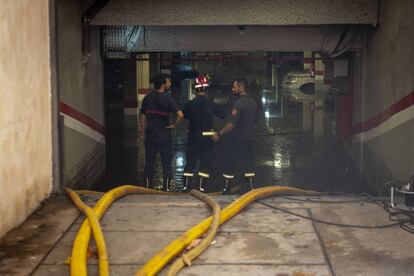 Bomberos trabajan en la entrada de un aparcamiento afectado por las inundaciones en el barrio del Raval.